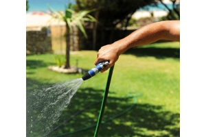 Mano sosteniendo una manguera de jardín mientras riega