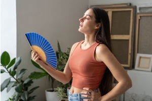 Mujer abanicándose en un espacio interior