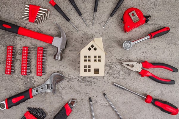 Kit de herramientas de bricolaje con martillo, destornilladores, alicates y llaves alrededor de una maqueta de una casa