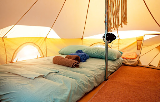 Tienda de campaña llena de colchones hinchables, almohadas y toallas